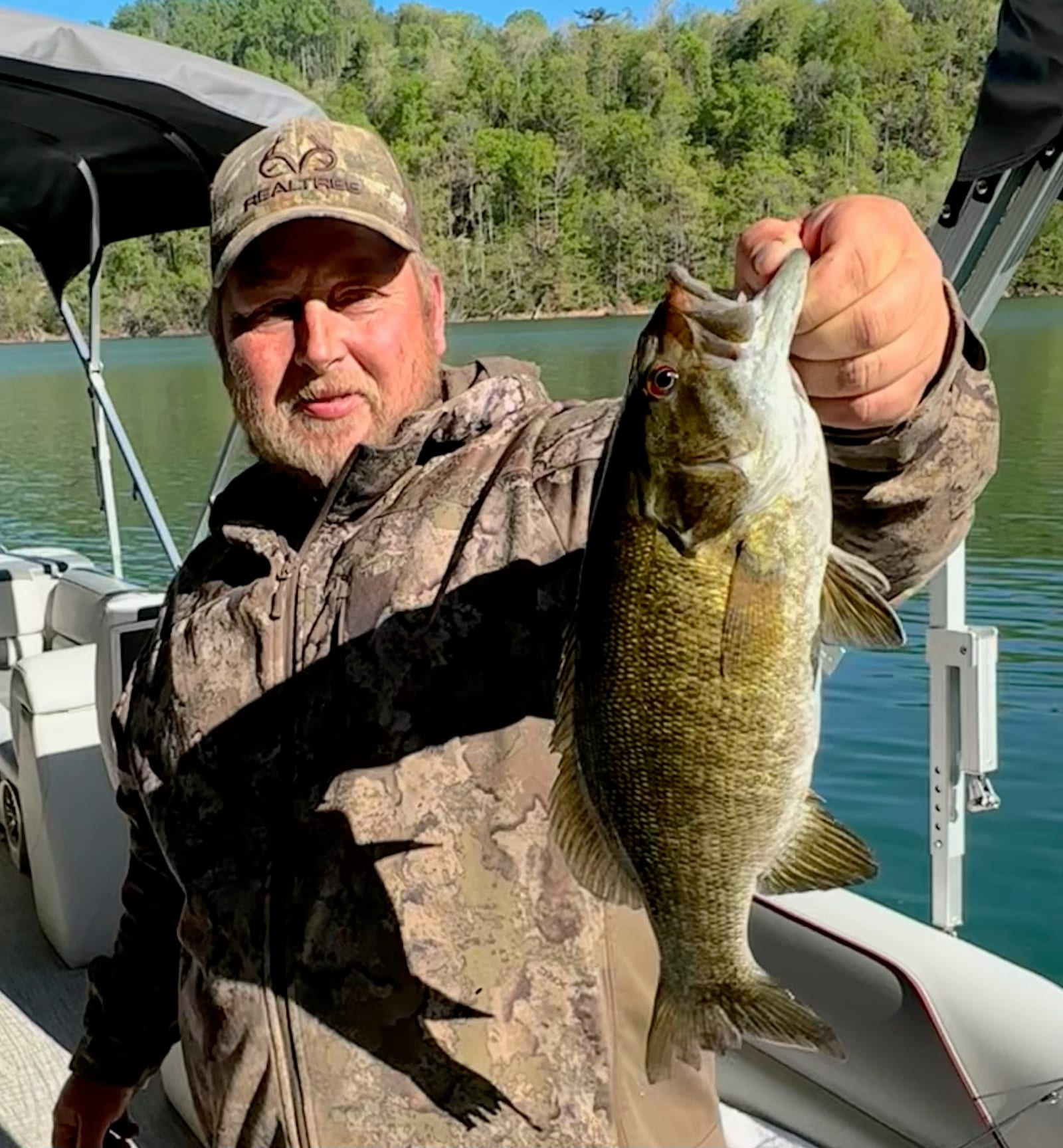 An angler holding a freshly caught smallmouth bass on Watauga Lake.