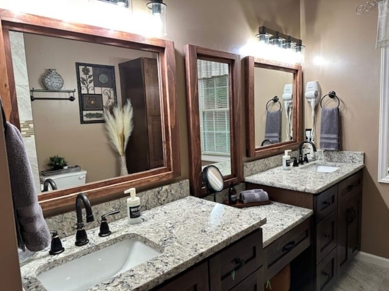 Granite-counter ensuite bath with dual sinks and framed mirrors.