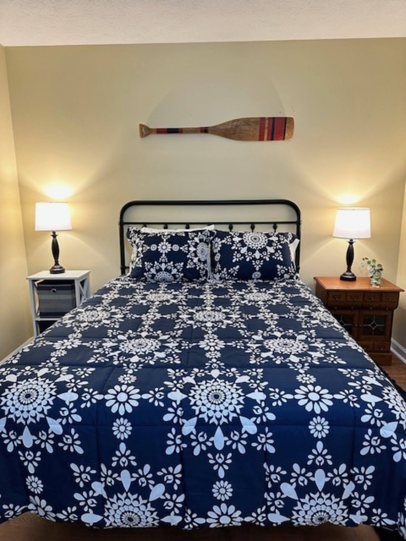 Primary bedroom with king bed, ceiling fan, and natural light from large windows.