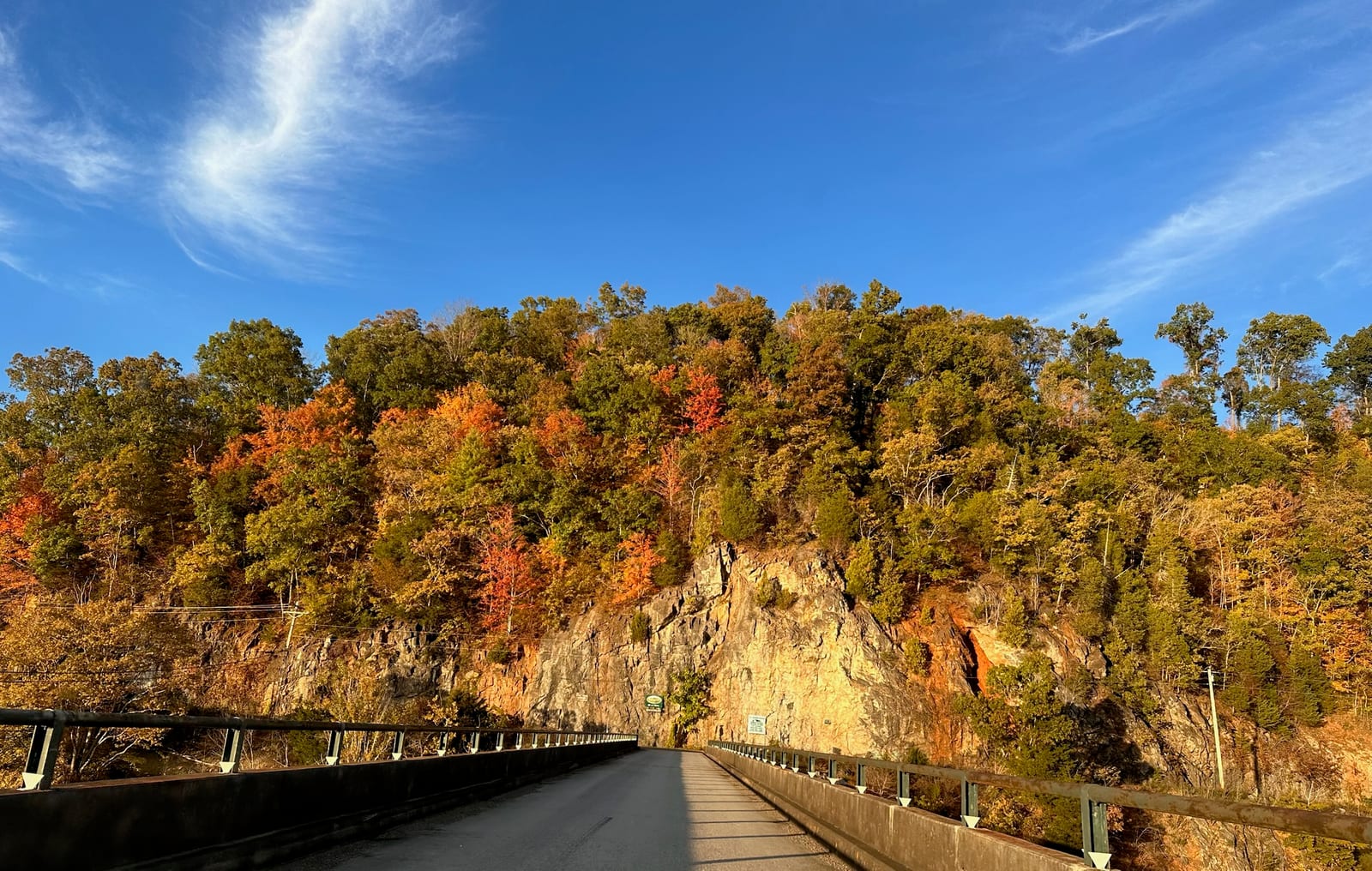 A road leading toward Watauga Dam framed by peak fall foliage on the surrounding ridges.