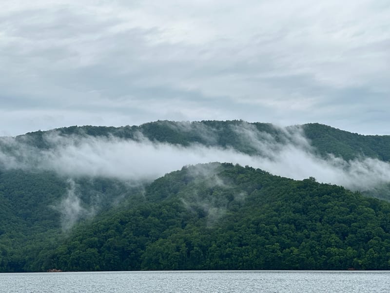 Low clouds drifting over green mountains above Watauga Lake on a summer morning.