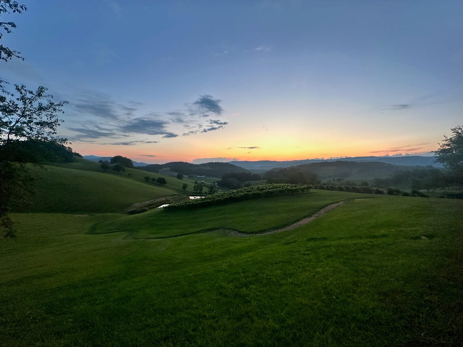 An open pasture near Watauga Lake at sunset, with the surrounding mountains in golden light.