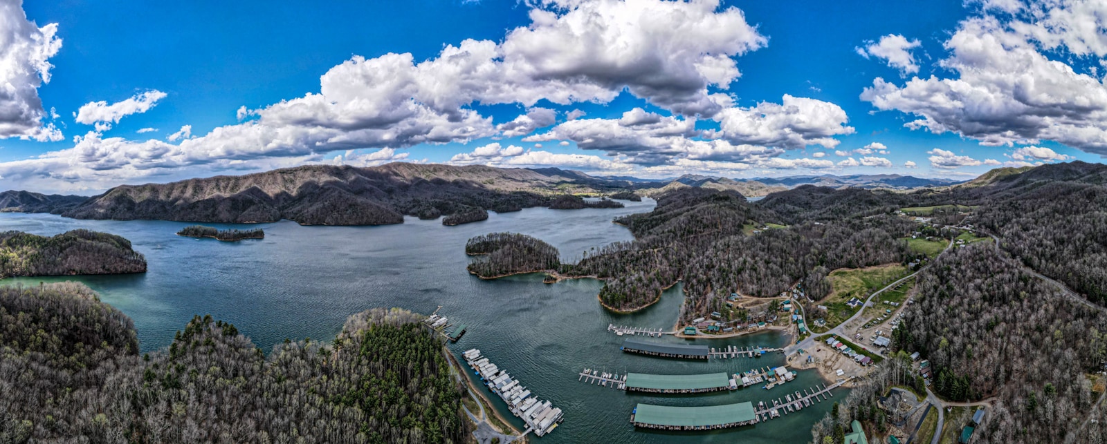 Aerial panorama of Watauga Lake from above the Watauga Lakeshore Marina, showing the lake stretching west into the Cherokee National Forest with the docks in the foreground.
