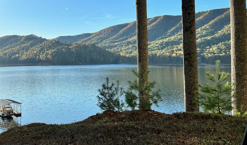 Watauga Lake with a small dock and fall-colored mountains in morning light.